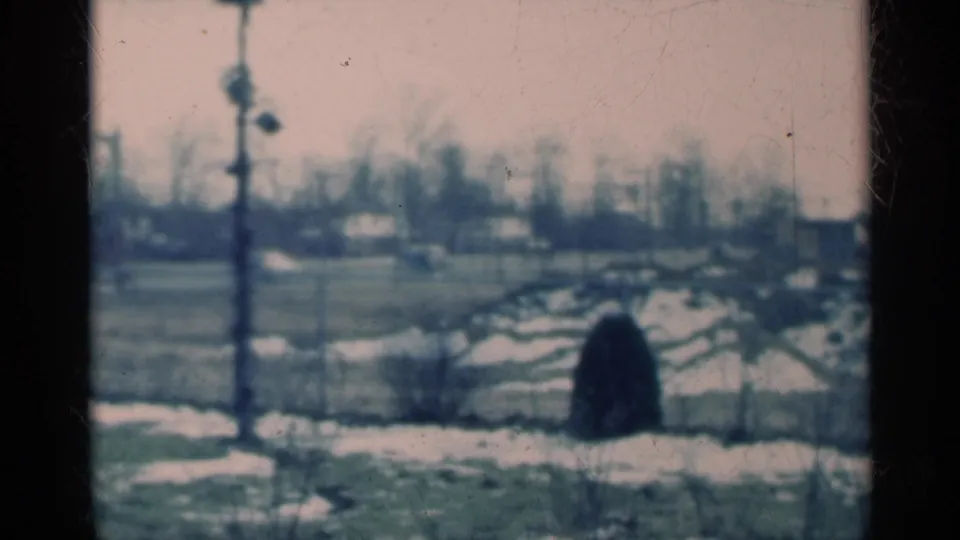 1939 Michigan 8mm frame of a static rural winter landscape with snow patches, distant homes, bare trees, and faded color.