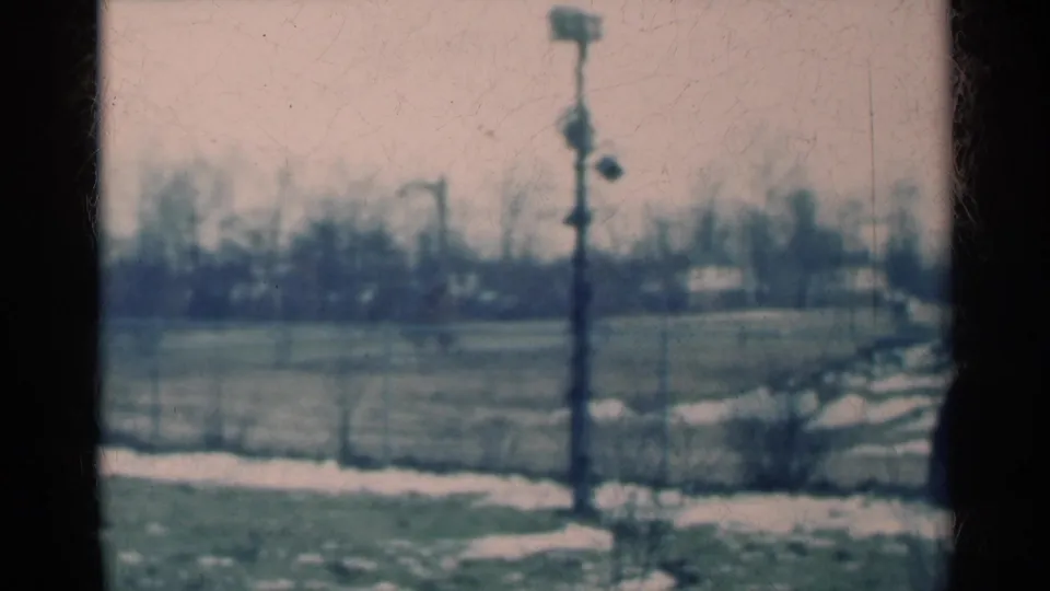 1939 Michigan 8mm still with a central utility pole, patchy snow on grass, a pale path, and soft distant trees.