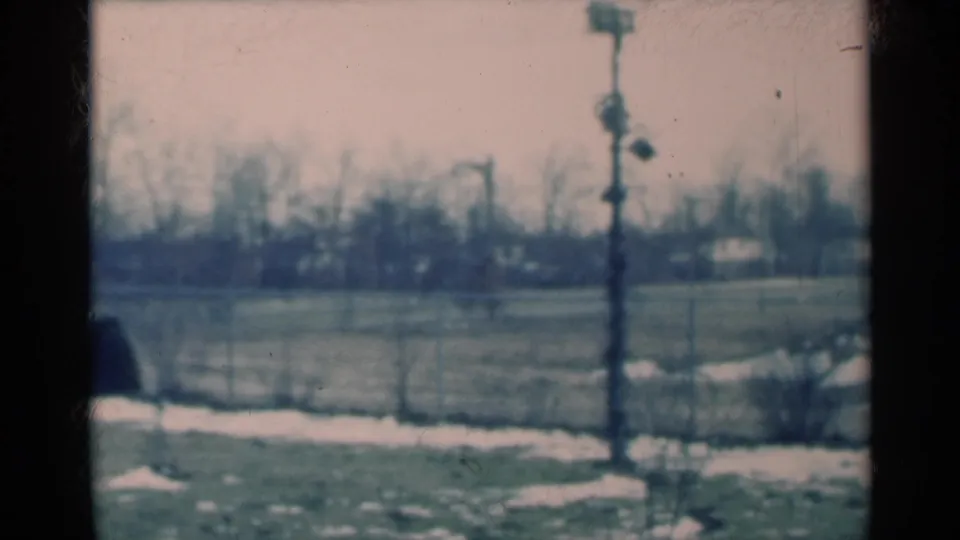 1939 Michigan rural frame showing a snow-patched field, utility pole, bare horizon trees, and a dark rounded form partly cut off at left.