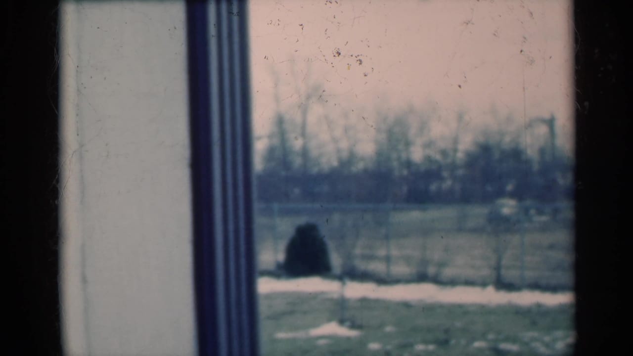 1939 Michigan 8mm frame with interior window trim in the foreground and a blurred winter yard, fence, snow patches and bare trees beyond.