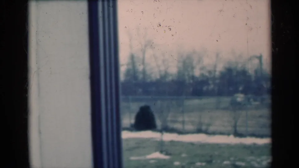 1939 Michigan 8mm frame with interior window trim in the foreground and a blurred winter yard, fence, snow patches and bare trees beyond.