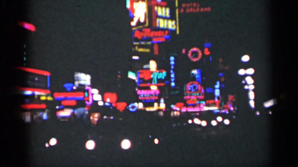1949 New Orleans nighttime cityscape with multiple neon signs, streetlights, and blurred traffic lights against a dark sky.