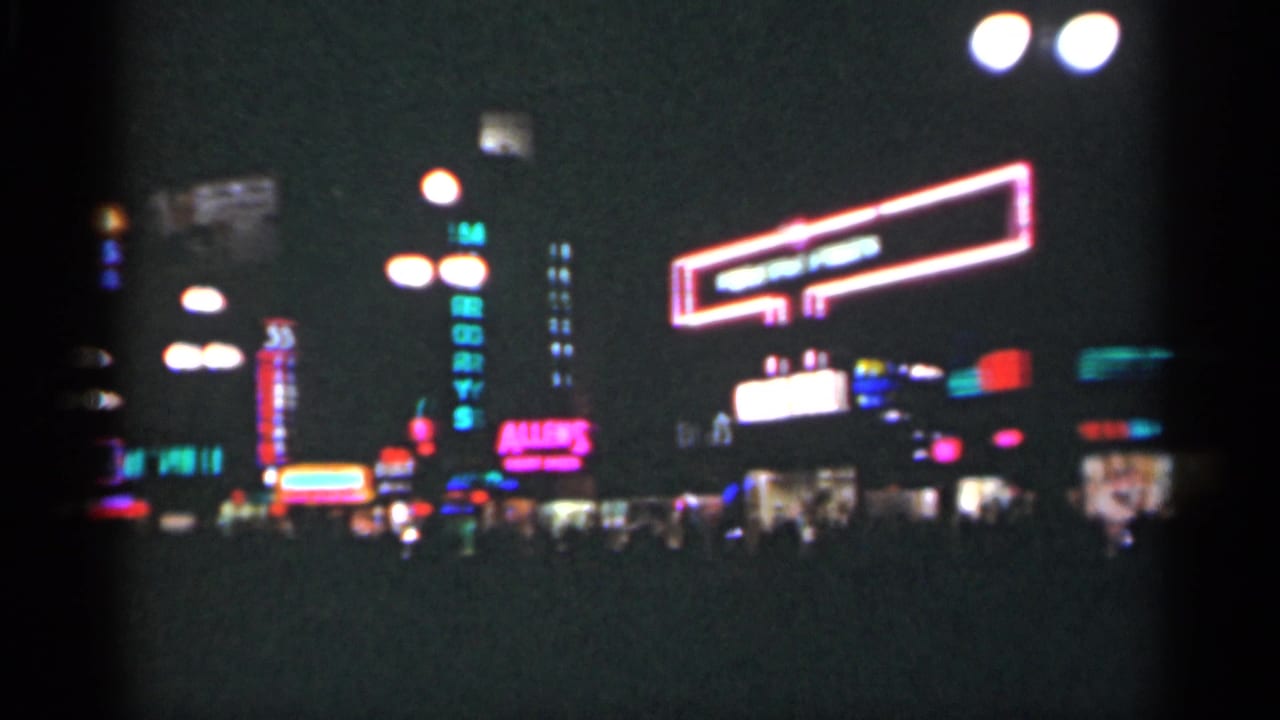 Neon-lined night street with a large outlined sign and storefront lights.