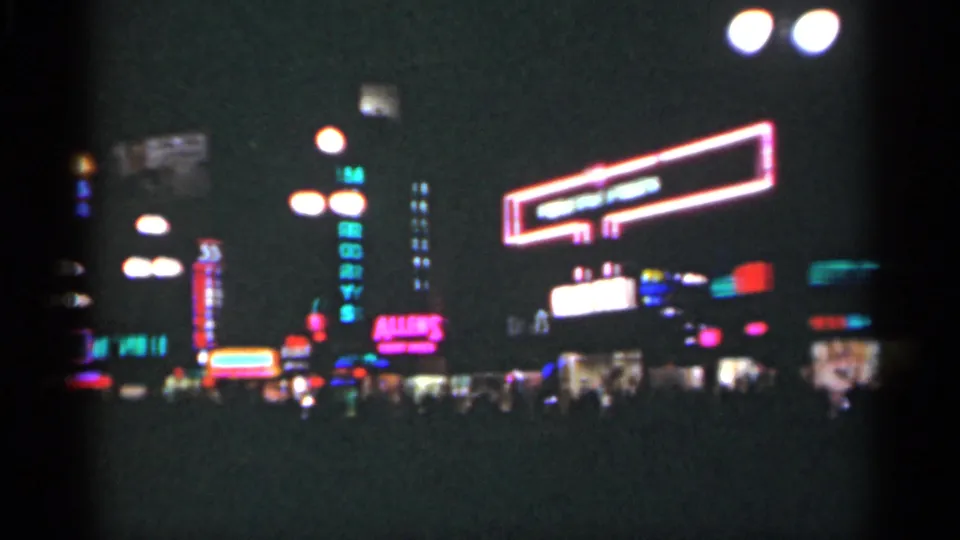 1949 New Orleans nightlife view with a large outlined neon sign, vertical lights, storefront glow, and dark figures near the curb.
