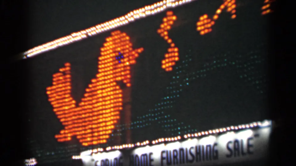 1949 New Orleans 8mm frame showing a glowing orange bird-shaped sign, musical-note lights, and a home furnishing sale banner at night.