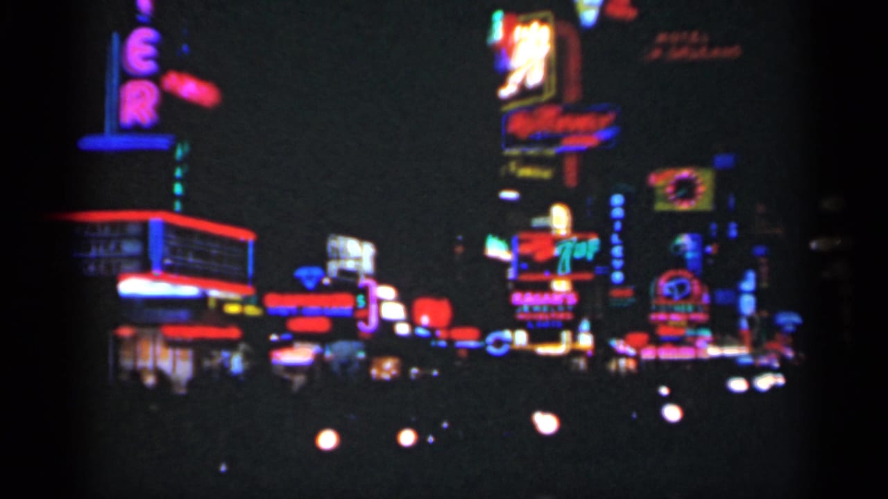 Night street lined with colorful neon signs and blurred car headlights.