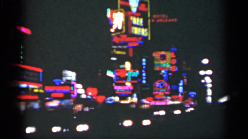 1949 New Orleans 8mm frame showing a dense cluster of glowing commercial signs above nighttime traffic.