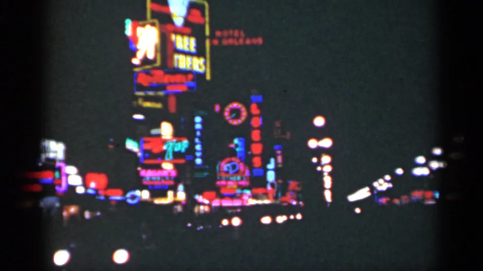 1949 New Orleans night street view with clustered neon signs, blurred traffic lights, and dark 8mm exposure.