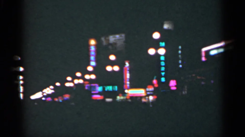 A 1949 New Orleans night street scene shows receding streetlights, colorful neon signage, and dark storefront outlines.