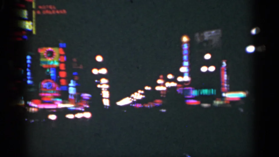 1949 New Orleans footage shows vertical neon displays, glowing streetlamps, and deep shadows in a handheld 8mm night view.
