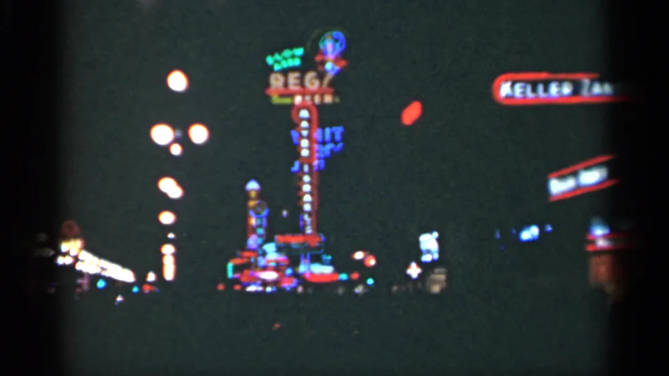 1949 New Orleans night frame showing a neon sign cluster, round streetlights, and cropped commercial signage at the right edge.
