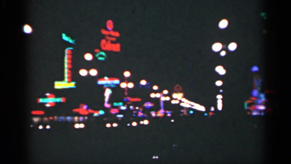 1949 New Orleans frame with scattered neon signs, bright lamp globes, and a low moving view across a commercial night scene.