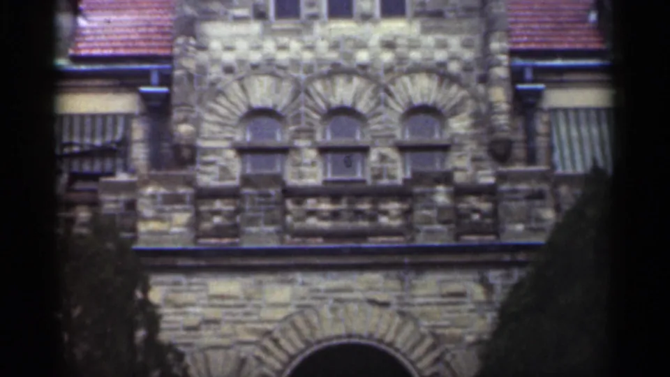 1949 New Orleans 8mm frame showing part of a grey stone church facade with arched windows, striped awnings, and red tile roof edges.