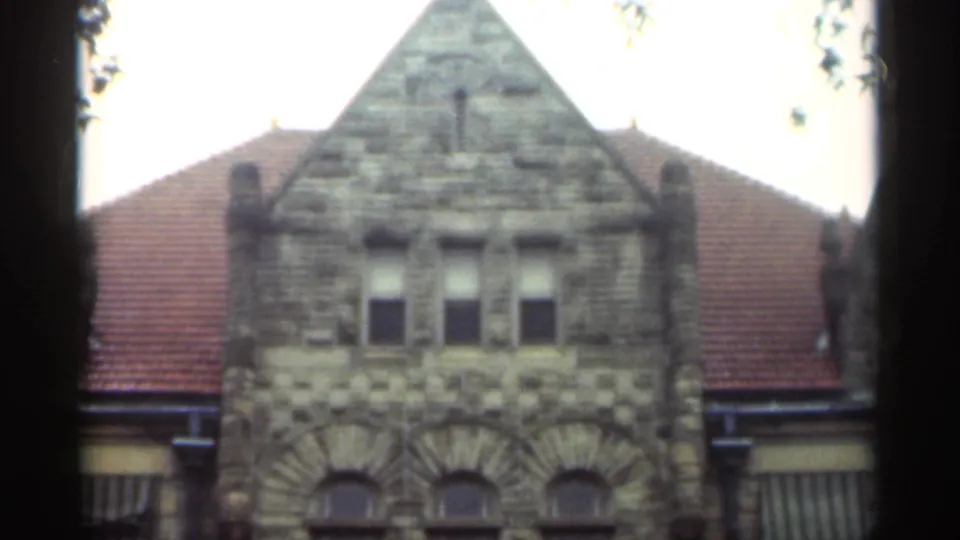 1949 New Orleans 8mm frame showing a gabled stone church front, rectangular upper windows, arched lower windows, and red tile roof sections.