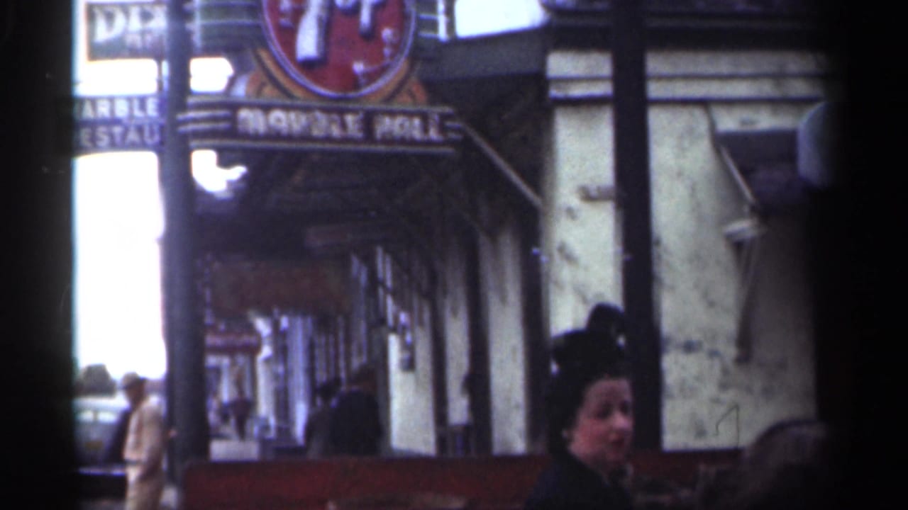Sidewalk storefront view with 7-Up sign, Marble Hall lettering, pedestrians, and building facade.