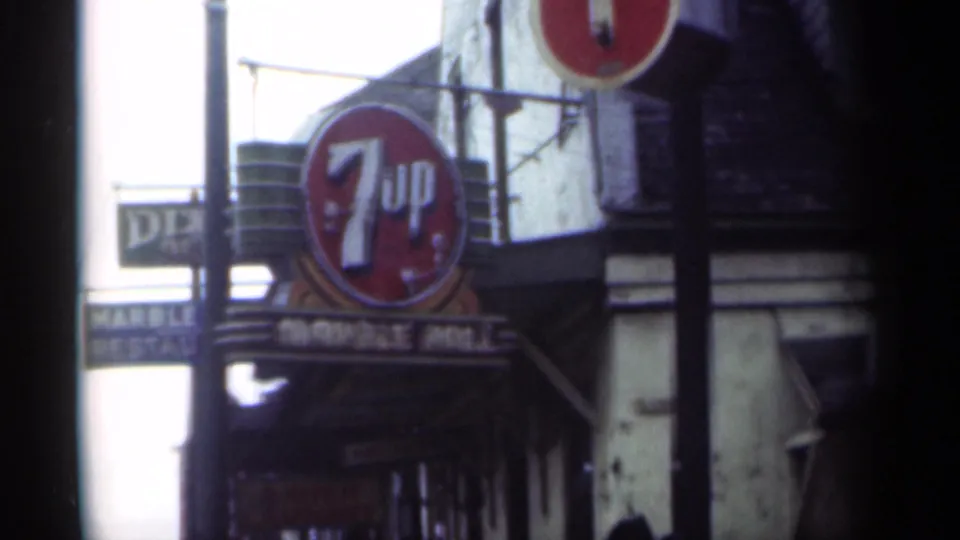 Tight 1949 New Orleans street detail showing a 7-Up sign, marquee trim, and adjacent vertical red sign.