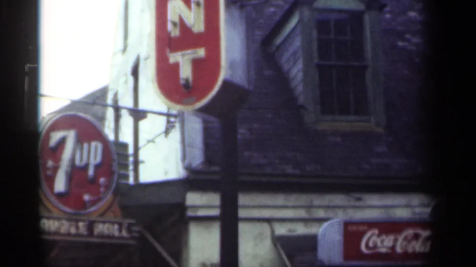 1949 New Orleans storefront detail with 7-Up signage, a vertical red sign, masonry facade, window, and partial Coca-Cola sign.