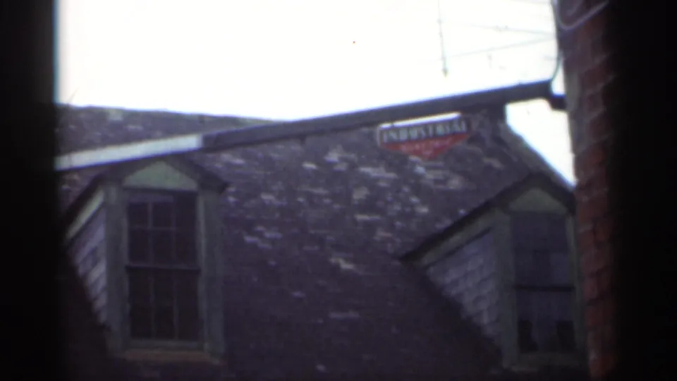 1949 New Orleans frame with weathered shingles, green-trimmed dormers, brick edge, and a small red sign above the Marble Hall roofline.