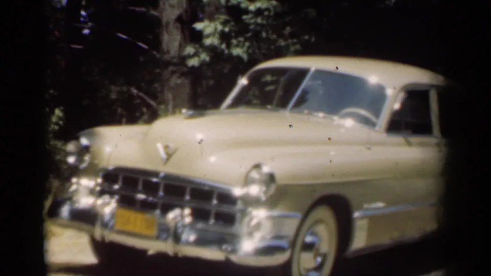 Front-left view of the cream Chevrolet sedan in the 1949 New Orleans home-movie clip, with chrome trim and trees behind it.