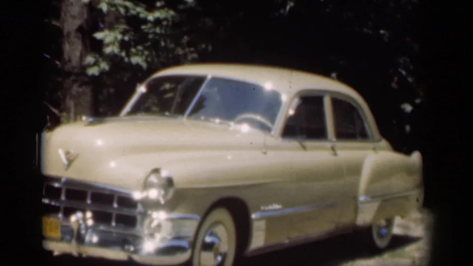 Cream mid-century Chevrolet sedan parked on a dirt driveway, with more of the passenger side visible in the 1949 New Orleans footage.