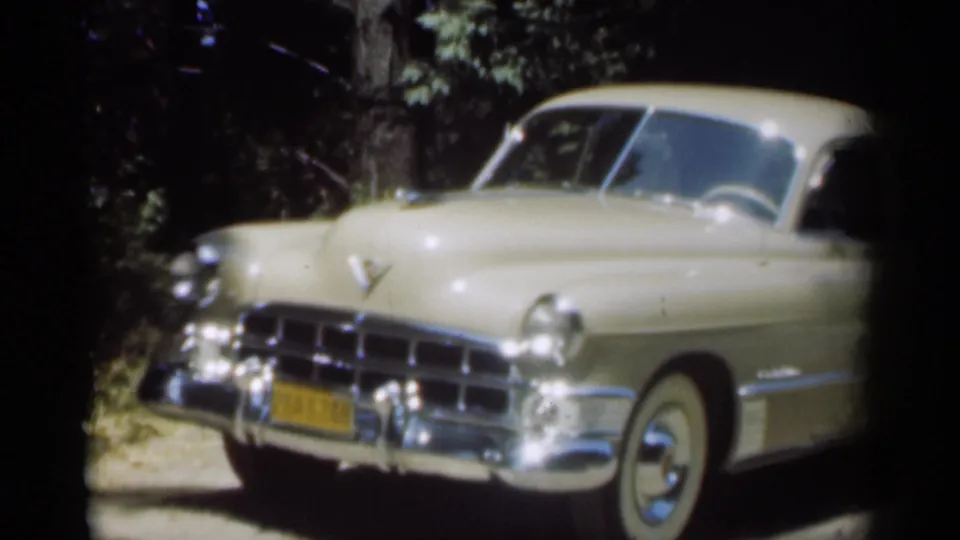 Close 1949 New Orleans home-movie view of the sedan front, showing a yellow plate, hood ornament, chrome grille, and whitewall tire.