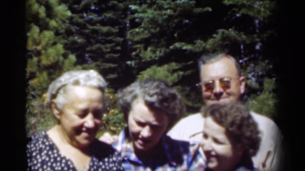 In metadata-supported 1949 New Orleans home-movie footage, four adults pose closely outdoors, including an elderly woman and a man in sunglasses.