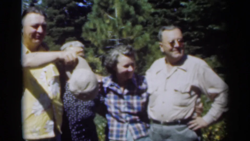 The 1949 New Orleans home-movie clip ends with adults spread across the frame in a sunny wooded area, including a man holding a hat.