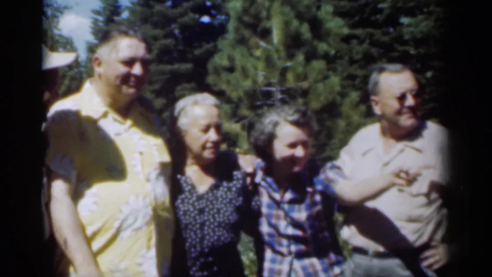 Four adults in 1949 New Orleans stand in sunlight near trees, smiling while looking toward the camera or nearby activity.