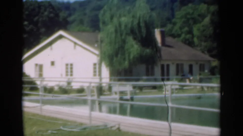 The Santa Cruz countryside scene holds on a farmhouse, willow, pond or pool, railings, and green trees in soft 8mm color.