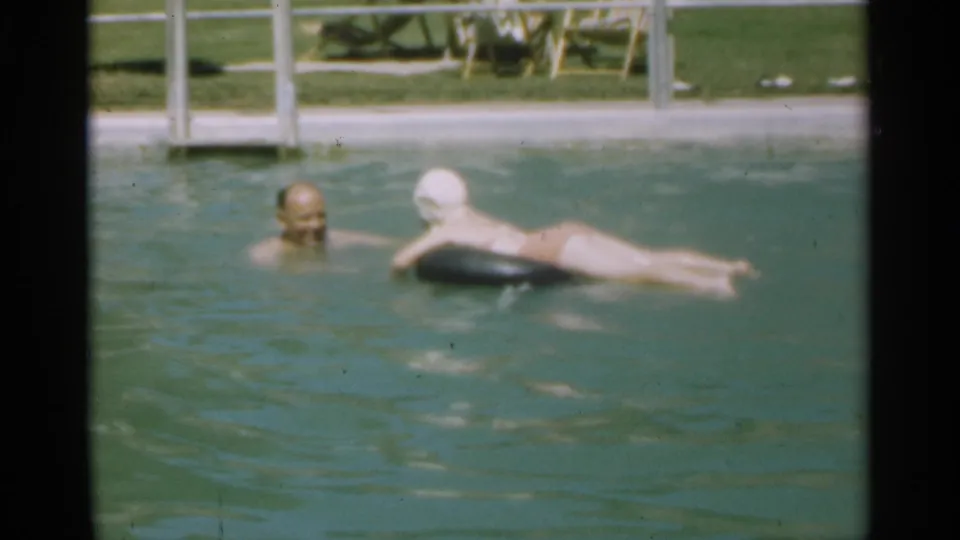 A father appears to smile while his daughter rests on the inner tube in the 1949 Santa Cruz public-pool scene.