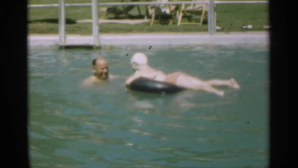 At the end of the Santa Cruz pool clip, the father and daughter are close together in the water beside the poolside fence and grass.