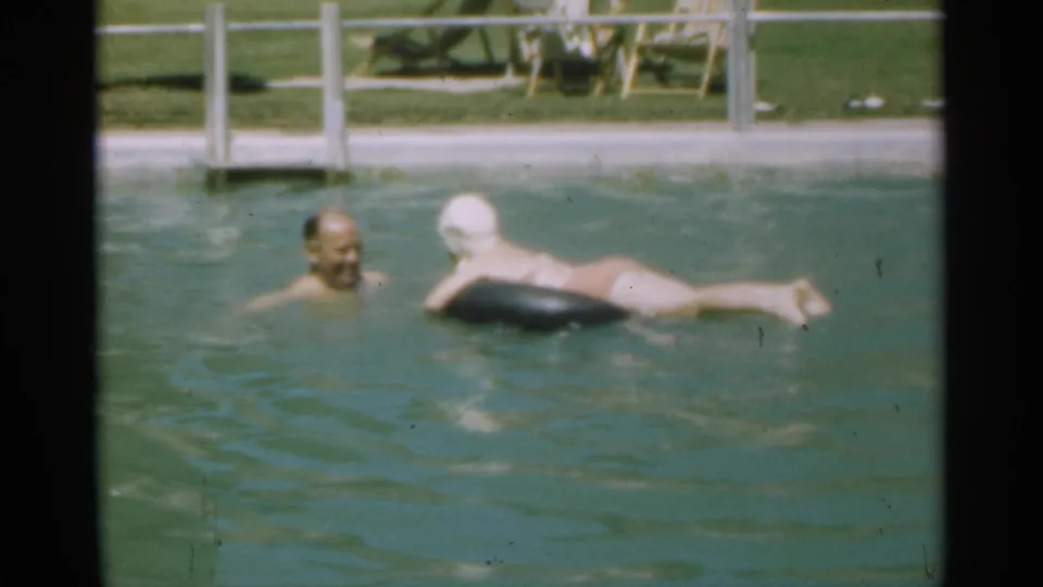 In 1949 Santa Cruz home-movie footage, an older man swims near a woman in a white swim cap floating on a black ring.