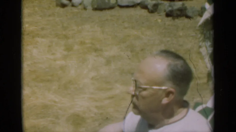 A closer 8mm frame shows the man with glasses in the yard, partly cropped by the handheld camera.