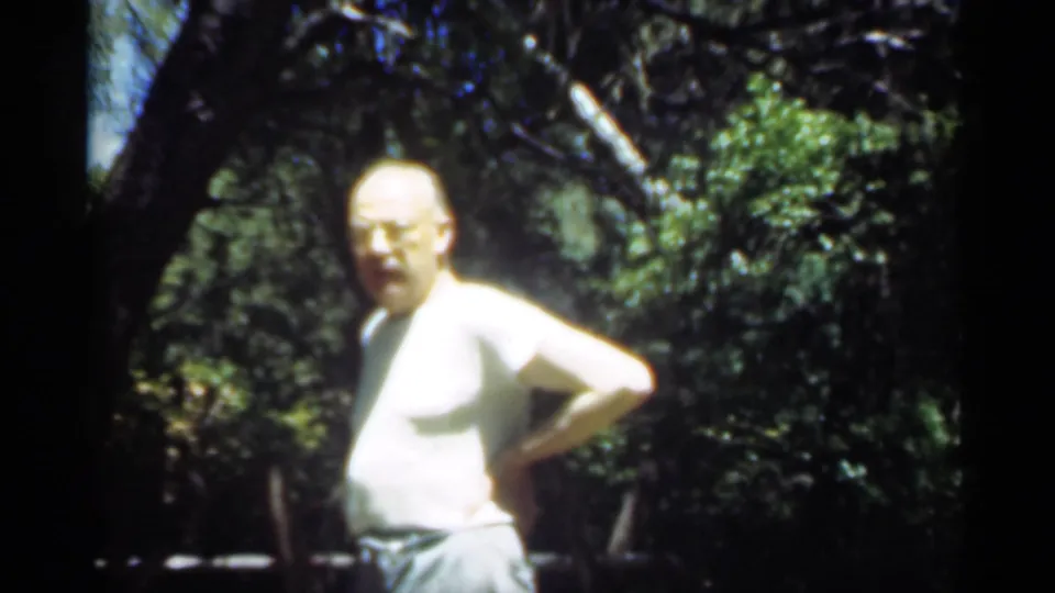 A man stands outdoors in wooded Santa Cruz scenery, with strong sunlight and soft 8mm exposure around his white shirt.