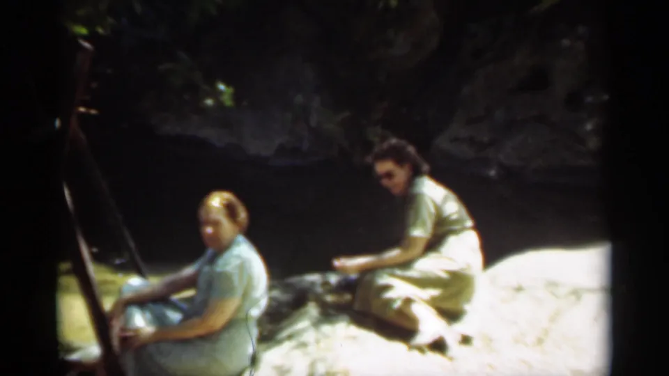 A closer 8mm frame shows two women on a rocky river edge in Santa Cruz, with strong sun on the foreground and shade behind them.