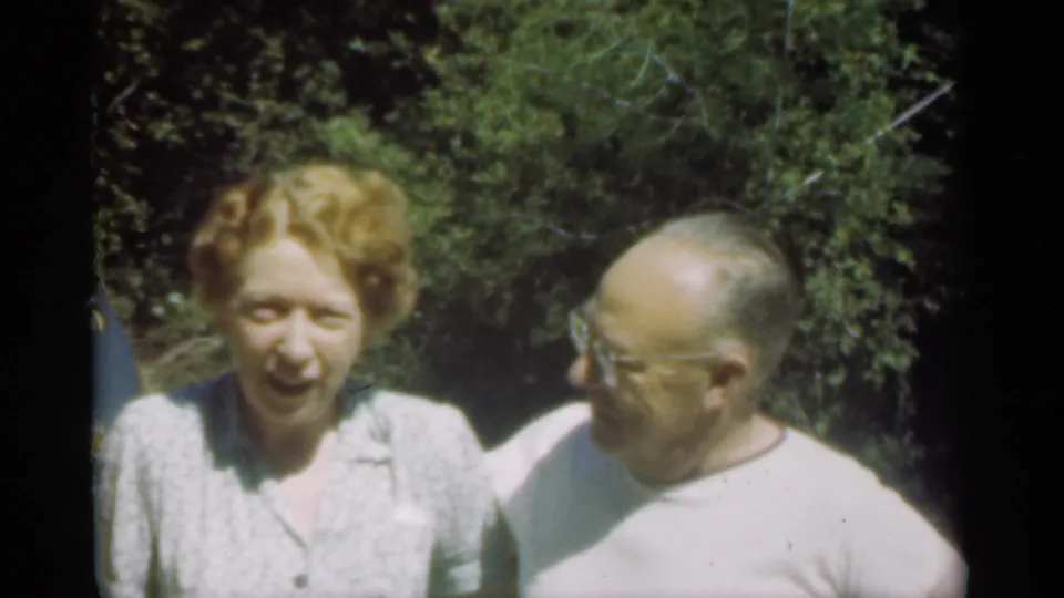 The woman faces the camera as the man in a white shirt looks across at her in the 1949 Santa Cruz outdoor scene.