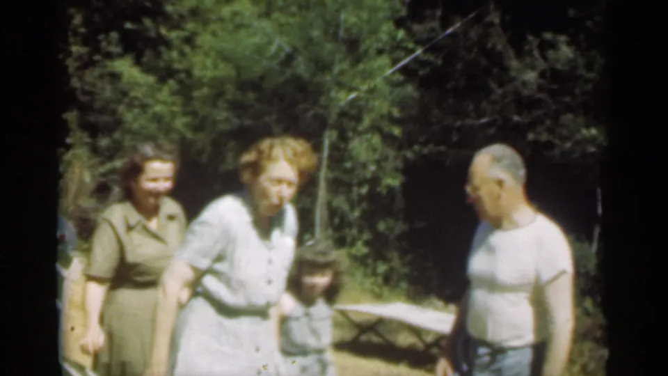 Three adults and a small child gather outdoors in Santa Cruz, with one woman bending slightly and a man standing aside.