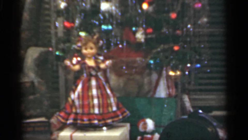 The final frame shows a doll in a plaid dress behind reflective glass, with indistinct display objects around it.