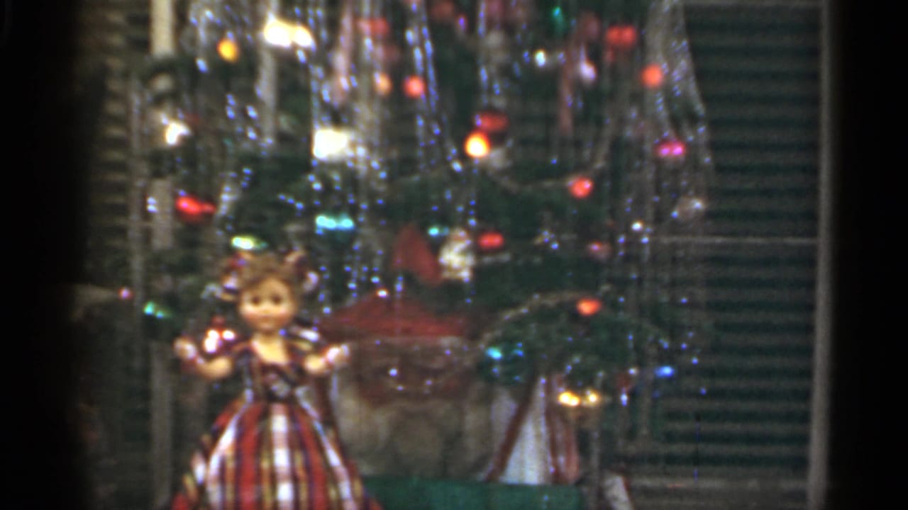 1949 Santa Cruz home-movie frame with a decorated Christmas tree, shiny tinsel, colored bulbs and a plaid-dressed doll near the lower left.