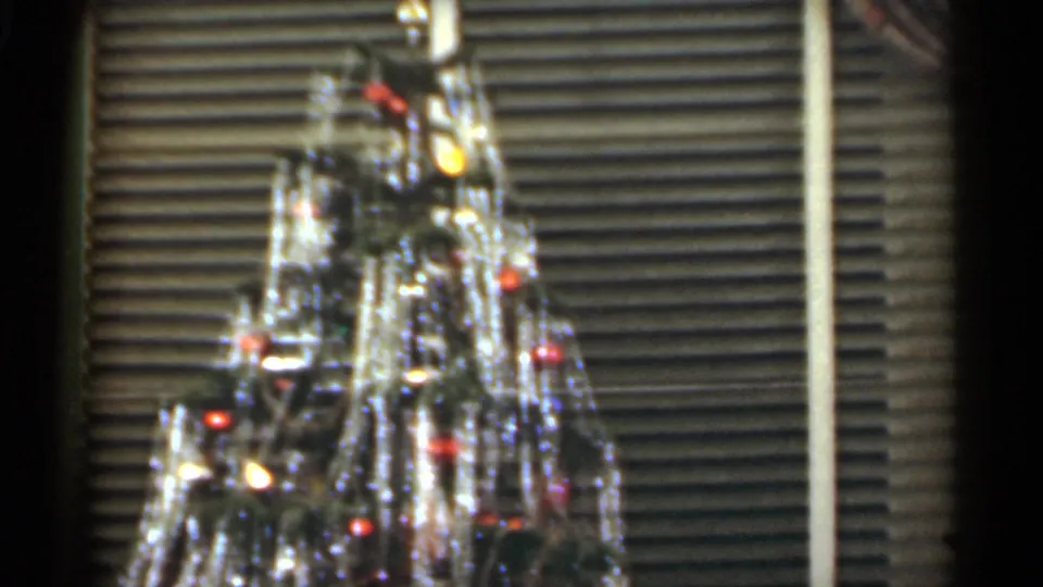 1949 Santa Cruz holiday frame with the upper Christmas tree, shiny tinsel, colored bulbs, and venetian blinds in the background.