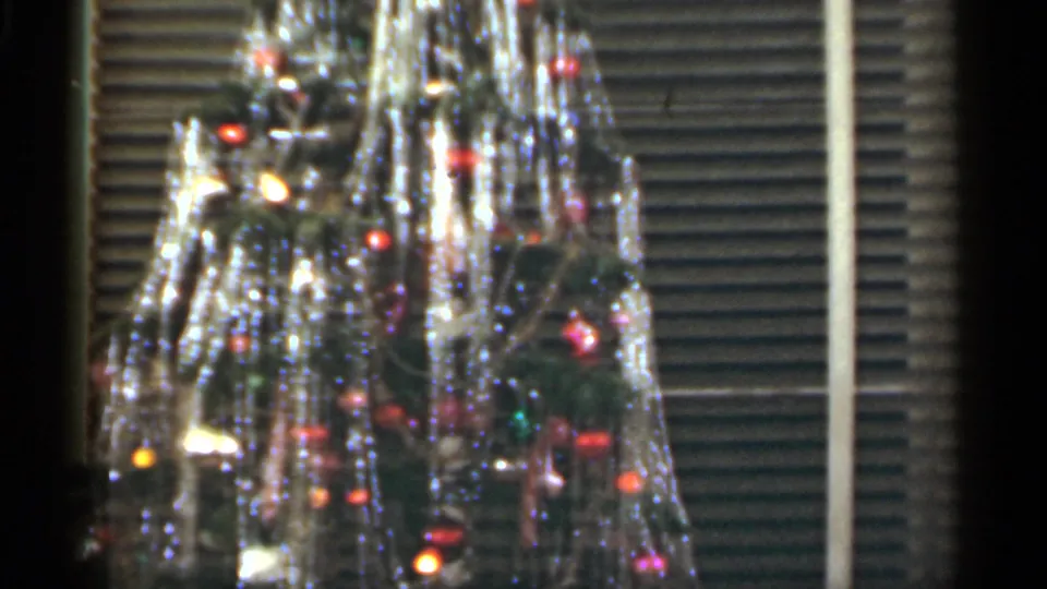 1949 Santa Cruz home-movie frame showing the upper portion of a tinsel-covered Christmas tree before window blinds.