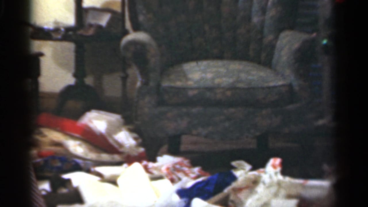A Santa Cruz living room appears with an upholstered chair, side table, and Christmas wrapping paper scattered across the floor.