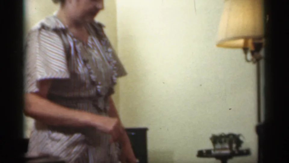 An adult in a striped dress is partly framed beside a lamp and side table in the 1949 Santa Cruz Christmas interior.