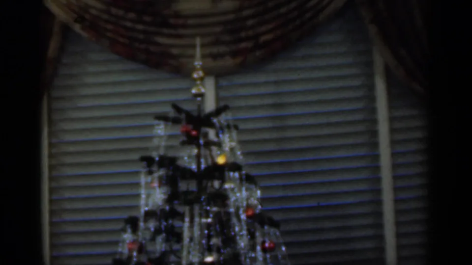 Decorated Christmas tree stands before venetian blinds in a 1949 Santa Cruz home interior, with ornaments and lights visible.
