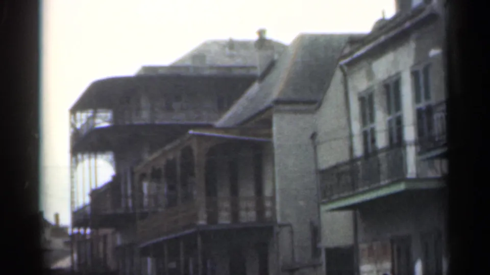 Santa Cruz, 1949 street detail showing balcony-fronted buildings, weathered facades, parked cars, and soft 8mm framing.