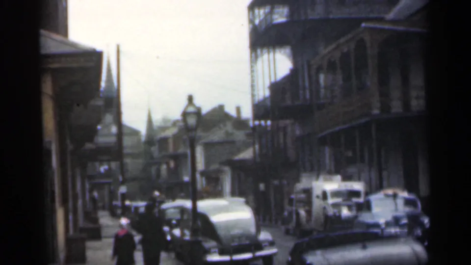 1949 Santa Cruz home-movie frame showing parked cars, pedestrians, apartment balconies, and a vintage street lamp.