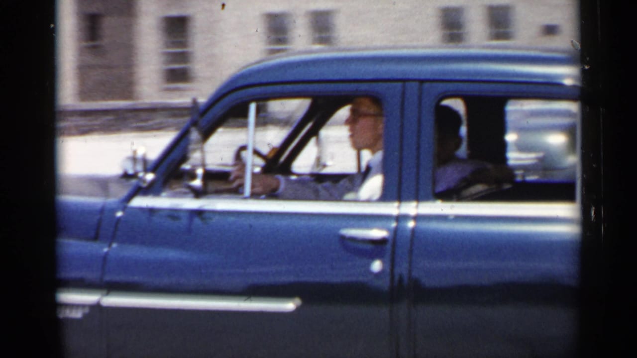 Blue sedan in side view with driver and rear passenger visible.