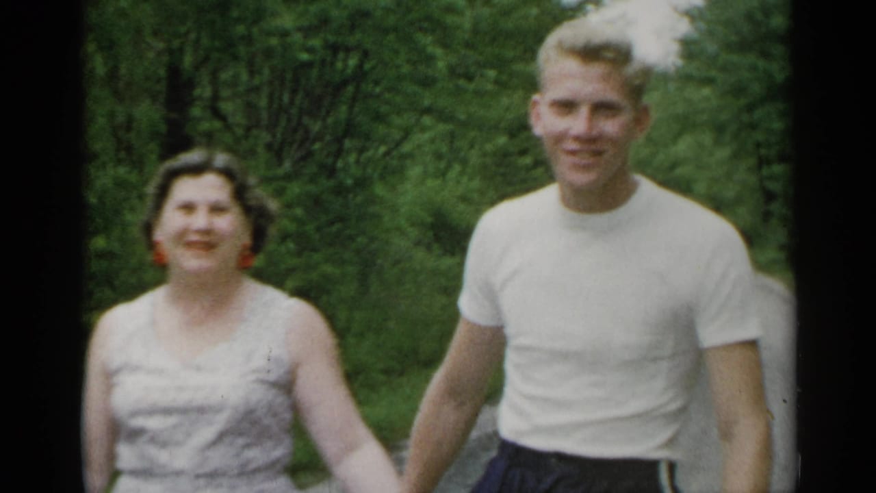 Smiling couple walking toward the camera in a leafy park.