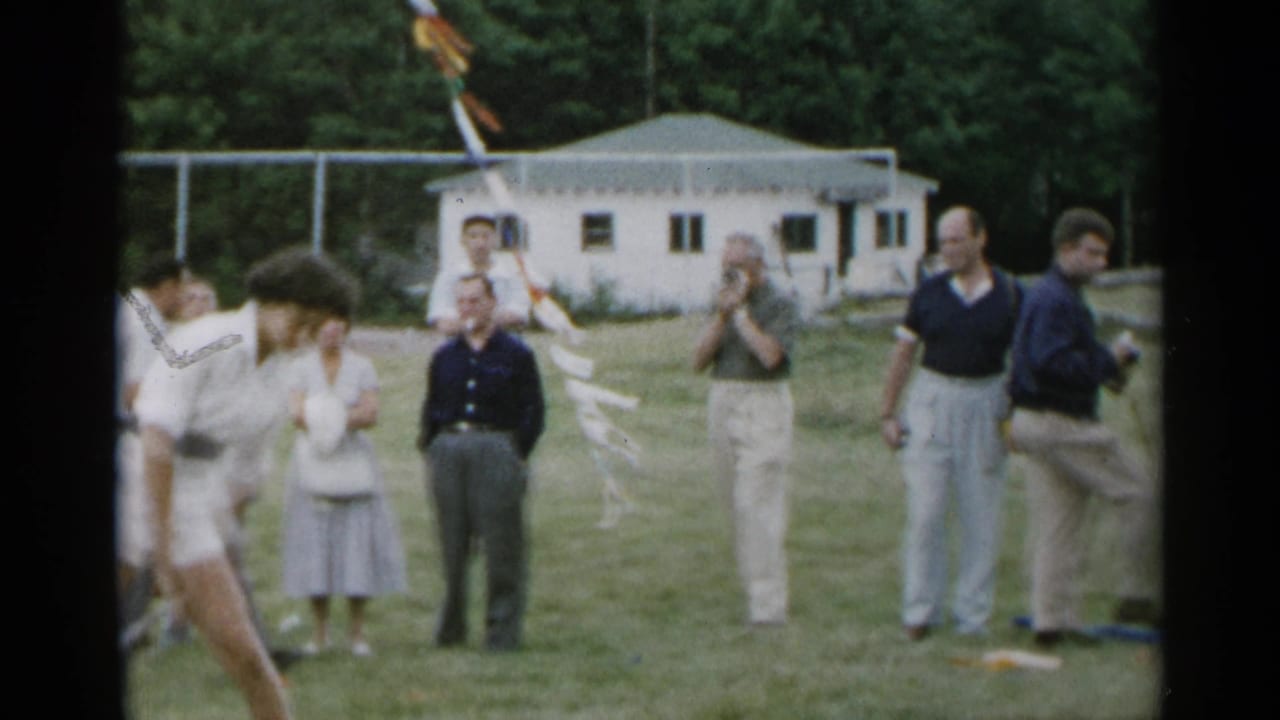 Onlookers stand near a field as the teen moves partly out of frame at left.