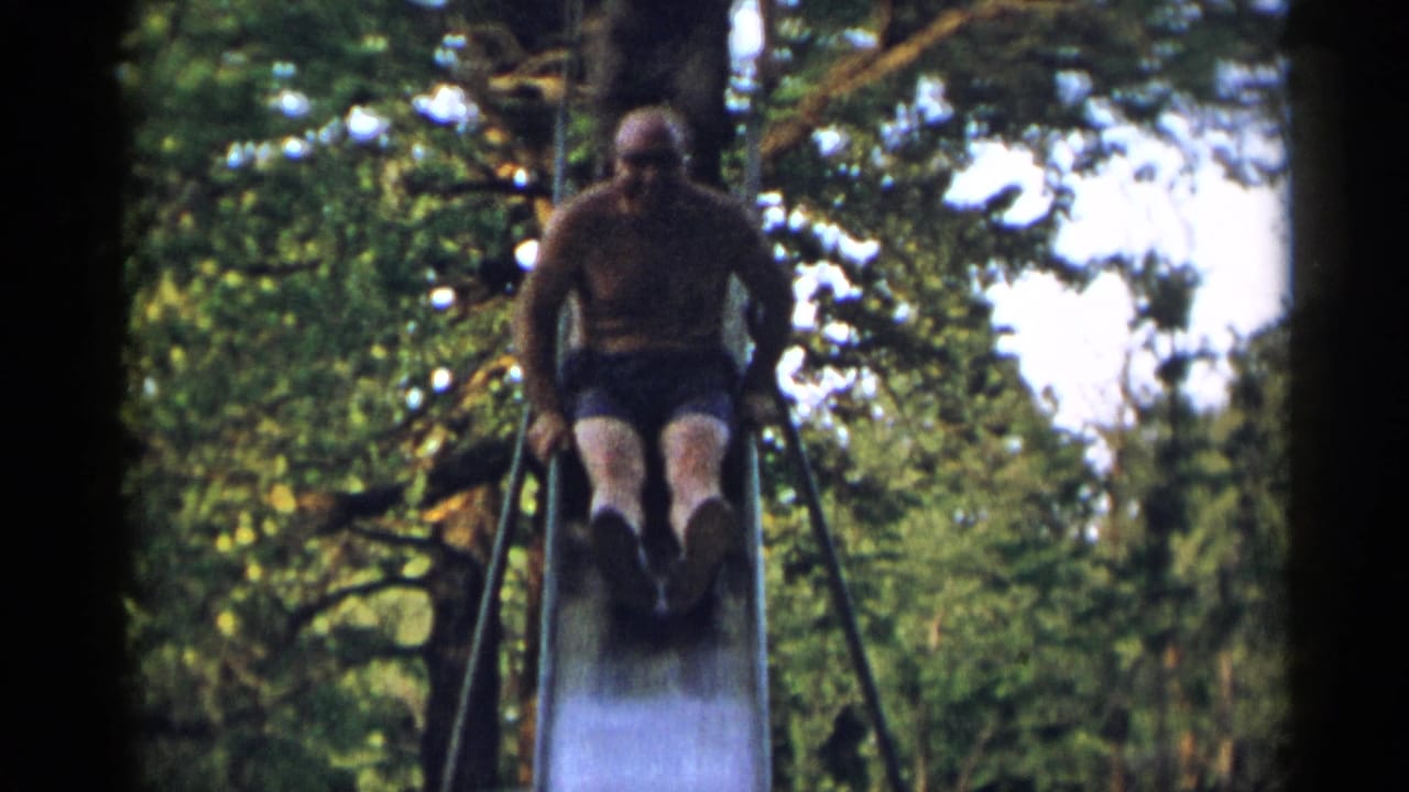 The shirtless older man starts down the metal slide, with ladder rails and leafy trees visible around him.